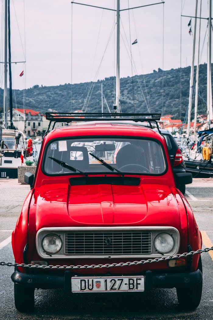 brand-03 Classic red Renault 4 car parked in Vela Luka, Croatia, with yachts in the background.