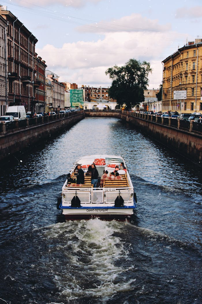 creative-02 A boat cruising through a picturesque canal surrounded by historic urban architecture, under a cloudy sky.